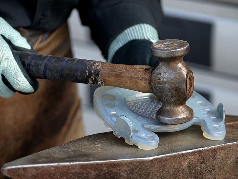 Modifizieren des zehenoffenen Verbundbeschlags mit dem Hammer für die Anwendung bei Hufrehe