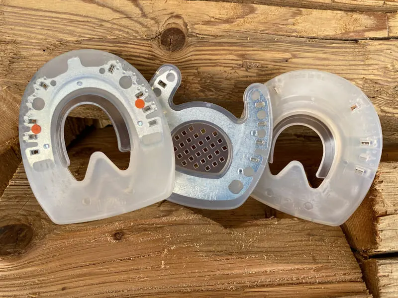 Drei Hufeisen: zehenoffener Rehebeschlag, Classic Kunststoffbeschlag und Nailless Verbundhufeisen, beide zum Kleben, ohne Noppen