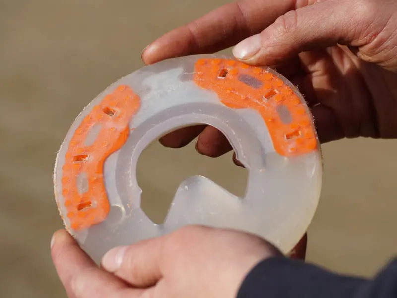 Verbundhufeisen mit abgeschliffenen Noppen in den Händen gehalten, modifizierter Kunststoffbeschlag für Pferdehufe