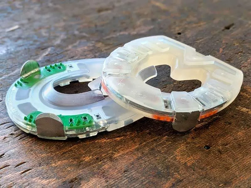 Ein Zehengewichtseisen mit Kunststoffmantel und Stahlverstärkung liegt in zwei verschiedenen Varianten auf einem Holztisch.