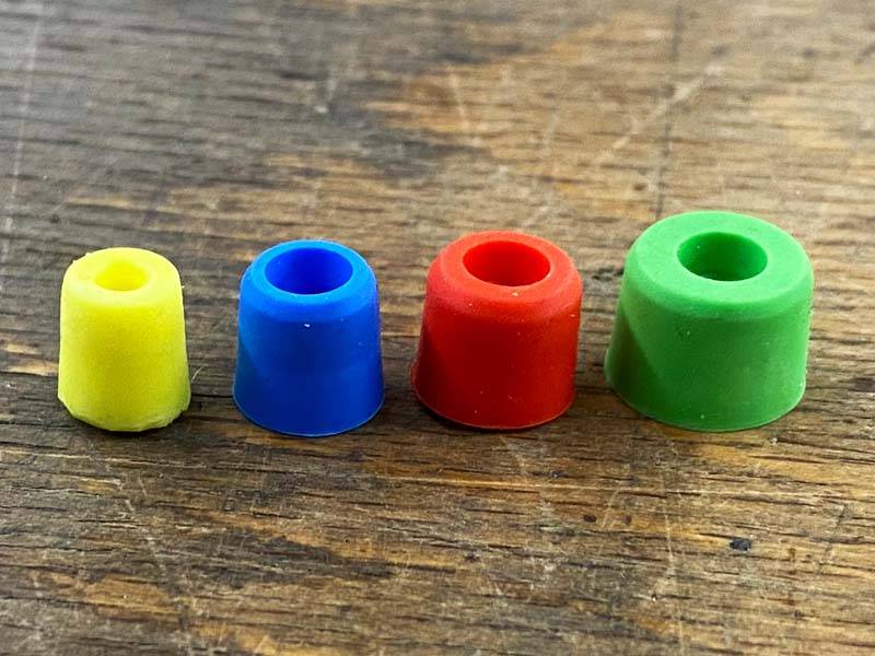 Kunststoffverschlussstopfen in verschiedenen Farben, zum Verschließen der Gewindelöcher in Hufeisen stehen nebeneinander auf einem Holzboden