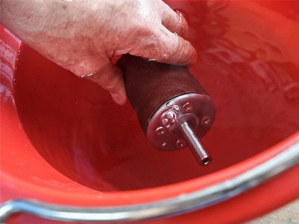 Der Hoof Buffer mit montiertem Schleifband wird unter Wasser gehalten. Dabei entweichen Luftblasen.