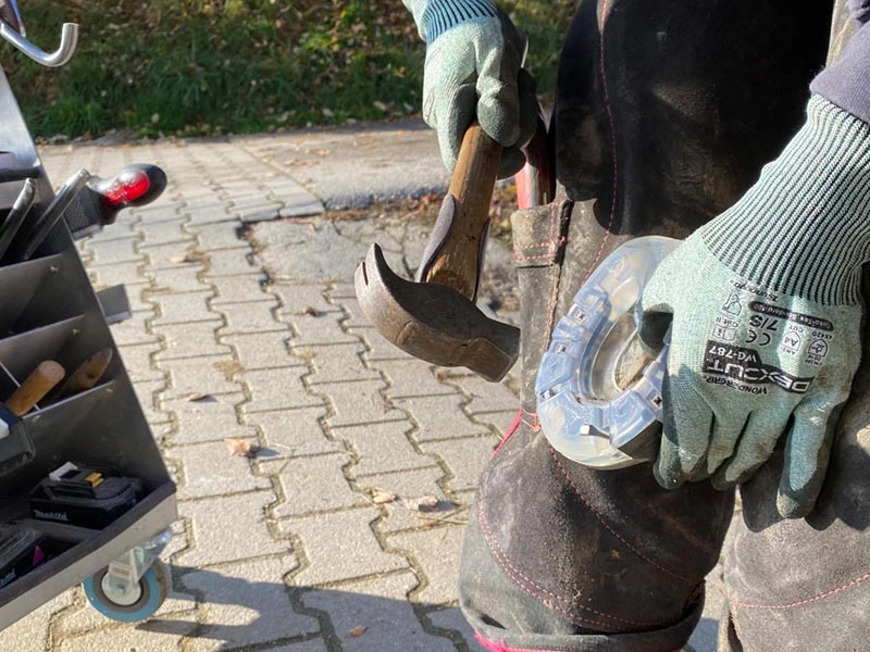 Ein Hufschmied nagelt mit einem Dick Hufbeschlaghammer mit Hickory-Hammerstiel ein Hufeisen auf einen Pferdehuf.