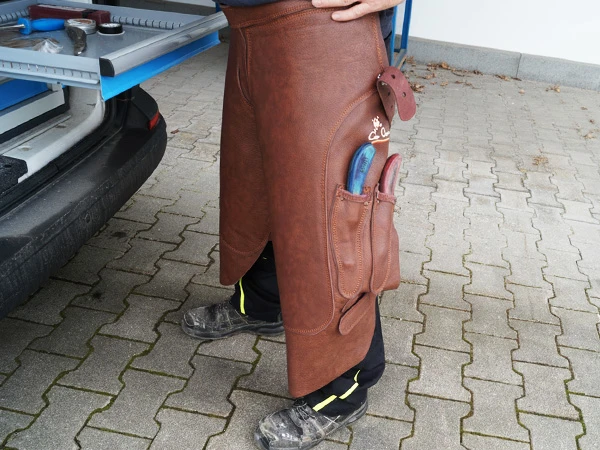 Ein Hufschmied trägt die Volllederschürze Elite lang in der Farbe braun.