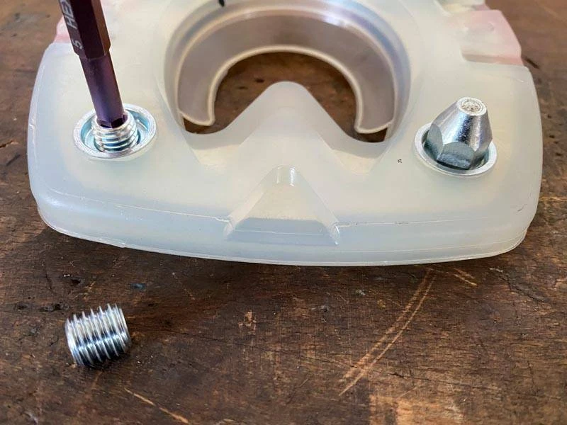 un tappo di chiusura metallico viene avvitato in un foro del rampone di un ferro di cavallo in materiale composito