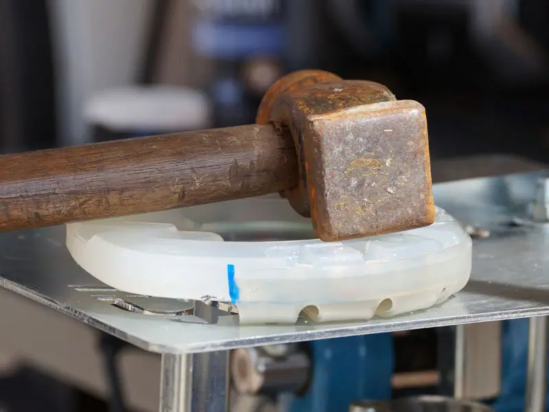 Un marteau repose sur une protection de sabot collée composée d’un fer Classic en plastique et d’un collier adhésif Easy.
