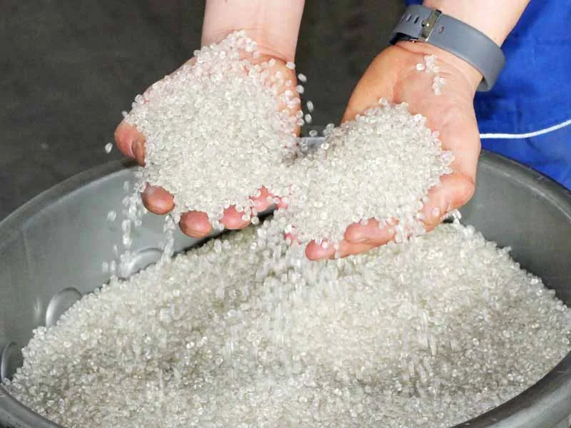 Granulat plastique pour fers composites tenu dans les mains.