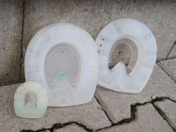 stossdämpfende Kunststoffbeschläge für Pferde in drei verschiedenen Ausführungen stehen nebeneinander.