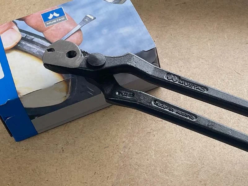 Eine Nagelziehzange von Mustad liegt auf einer Packung Hufnägel von Mustad.