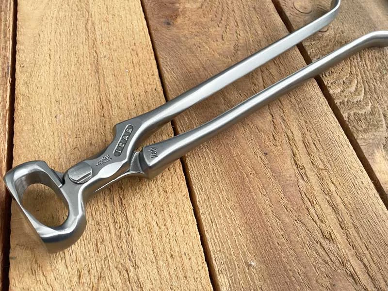 Une pince à parer ICAR posée sur un plancher en bois.