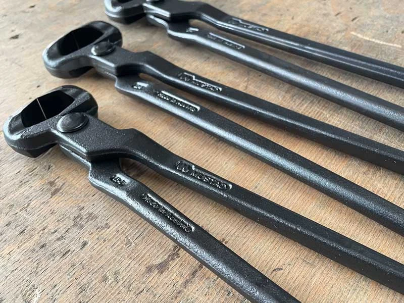 Les 3 modèles de pinces à parer Mustad posés sur un établi.