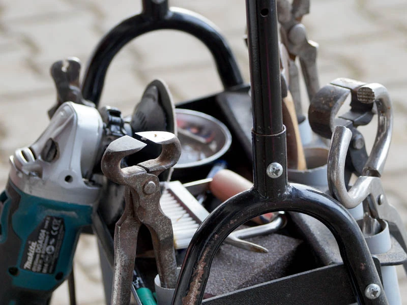 Chariot à outils d’un maréchal-ferrant avec divers outils ; au premier plan, une pince à parer.