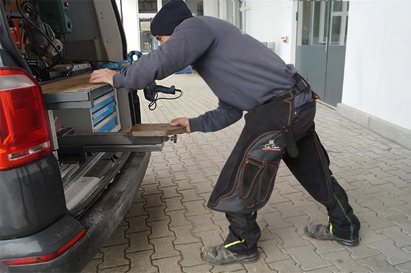 Die Con Cuero Schmiedeschürze Modell Olympic in Schwarz wird von einem Hufschmied getragen.