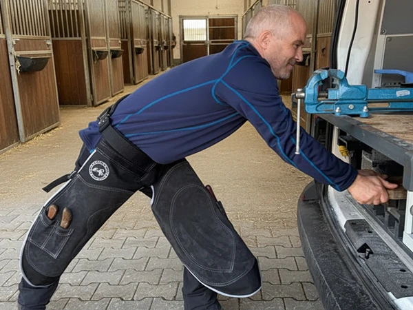 Ein Hufschmied bereitet seinen Beschlagbus für einen mobilen Einsatz vor. Er trägt eine Hufschmiedeschürze Hybrid Pro Chaps von Silverback.
