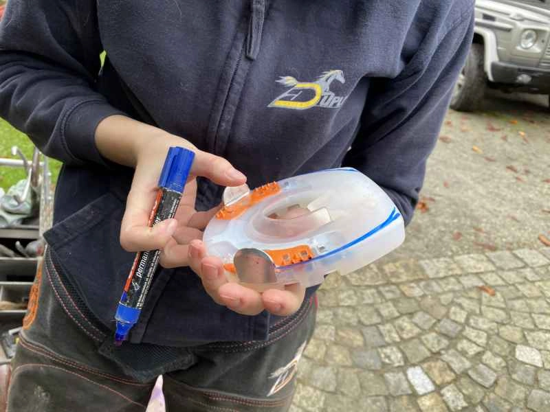 Die Hufschmiedin hält einen alternativen Beschlag in der Hand. Die Hufform des Pferdes ist bereits angezeichnet, aber der Beschlag wurde noch nicht angepasst.