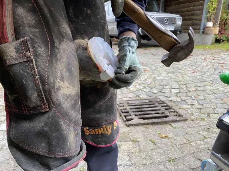Der Hufschmied beim Aufnageln eines alternativen Hufschutzes mit Aufzügen.