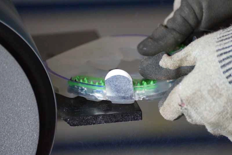 Der Hufschmied passt das Hufeisen mit Kunststoffmantel mit dem Bandschleifer an die exakte Hufform des Pferdes an.