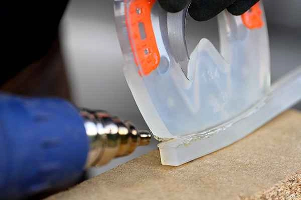 Der Hufschmied verlängert den Kunststoffmantel des Hufeisens im hinteren Bereich mithilfe eines Kunststoffschweißsteges. Dieser wird mithilfe eines Heißluftgerätes an den Beschlag geschweißt. 