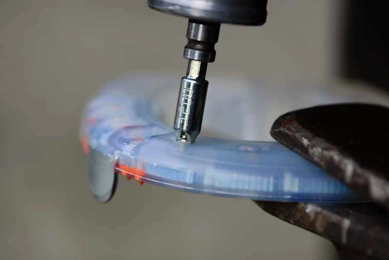 Mithilfe eines speziellen Spike Adapters und eines Akku-Schraubers werden die Spikes in den Kunststoffmantel des alternativen Hufeisens geschraubt. Der Hufschutz ist in einem Schraubstock fixiert.