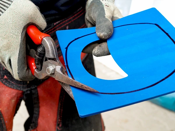 Un Sole Relief Pad carré avec une découpe en forme de croissant destinée à soulager la pointe de la troisième phalange est découpé à l’aide de ciseaux à cuir pour l’adapter à la forme de la protection de sabot.