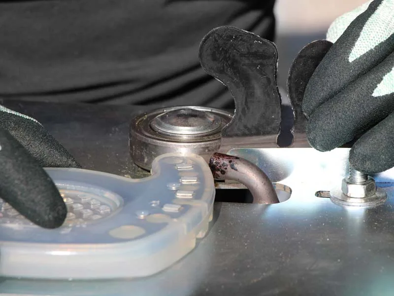 Hufschmied verschweisst einen zehenoffenen Beschlag mit einer Klebelasche mithilfe einer speziellen Vorrichtung