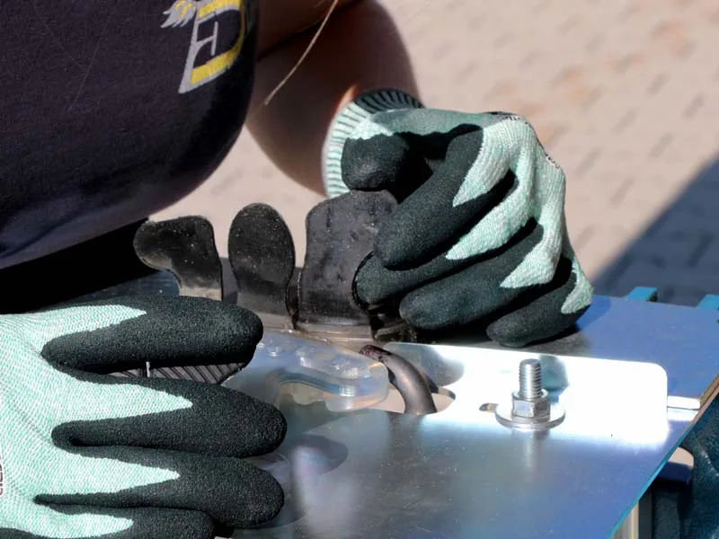 Hufbearbeiterin verschweisst einen zehenoffenen Beschlag mit einer Klebelasche, sie trägt Handschuhe und nutzt eine besondere Vorrichtung