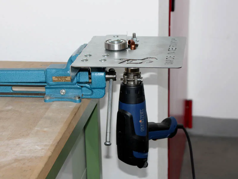 ein Heissluftgerät der Marke Steinel ist an einer Vorrichtung für das Herstellen von Klebehufeisen befestigt, die wiederum ist in einem hellblauen Schraubstock fixiert