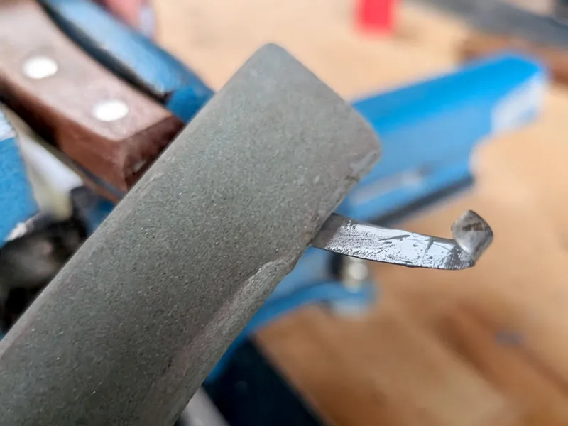 Der Hufschmied schärft ein Hufmesser mit einem Wetzstein aus Siliciumcarbid.